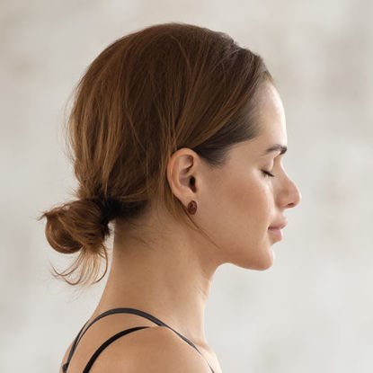 Frau im Profil mit geschlossenen Augen, entspannt, vor neutralem Hintergrund.